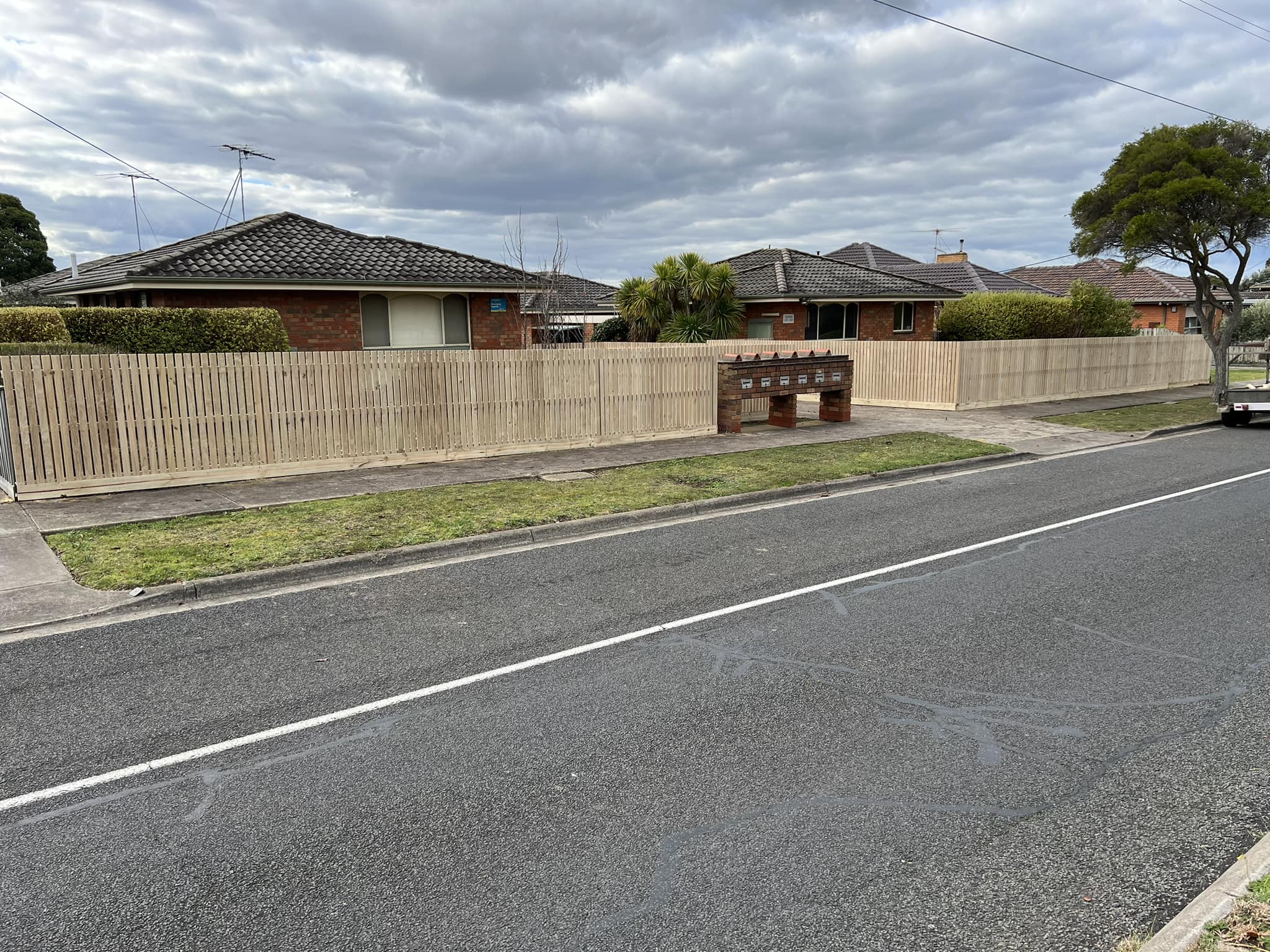 Long capped paling boundary fence along a quiet residential street