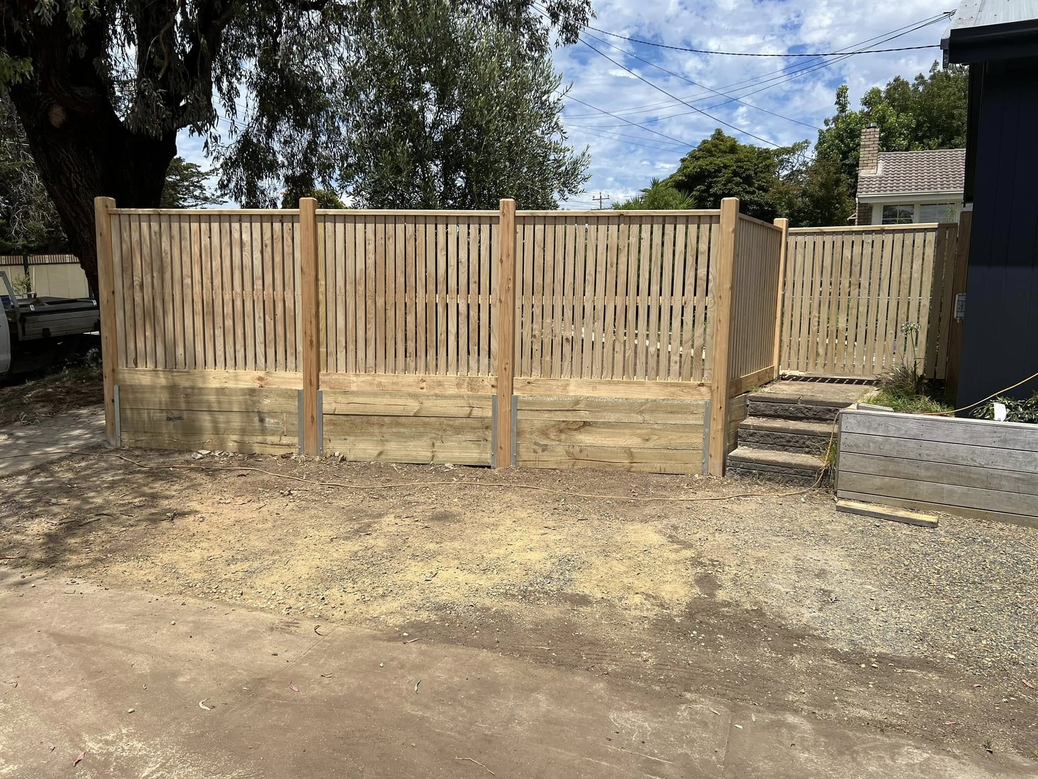 Capped paling fence on sleeper retaining wall base
