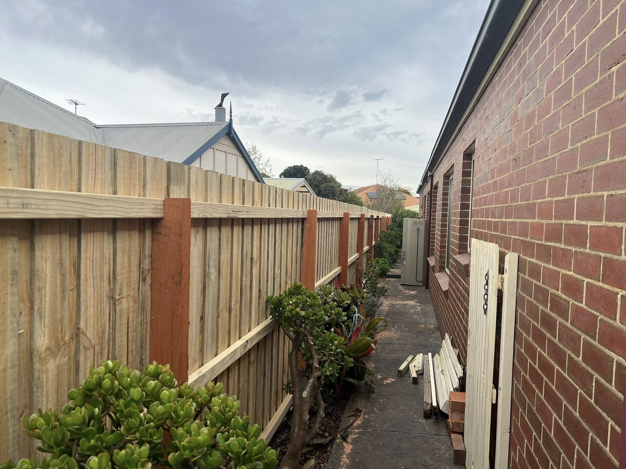 Paling fence along a brick-house side path