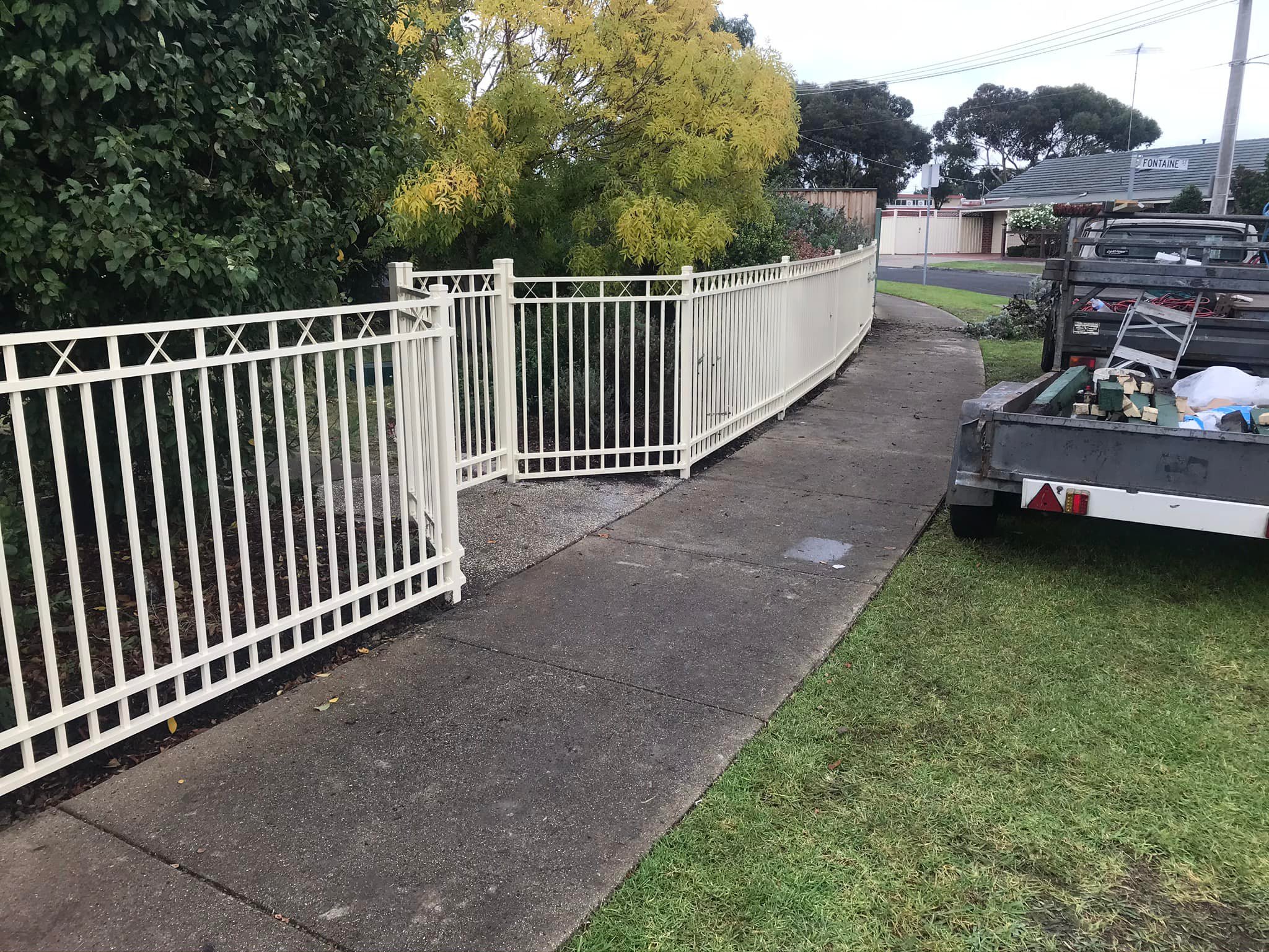 Cream tubular wrought-iron sliding gate with decorative top